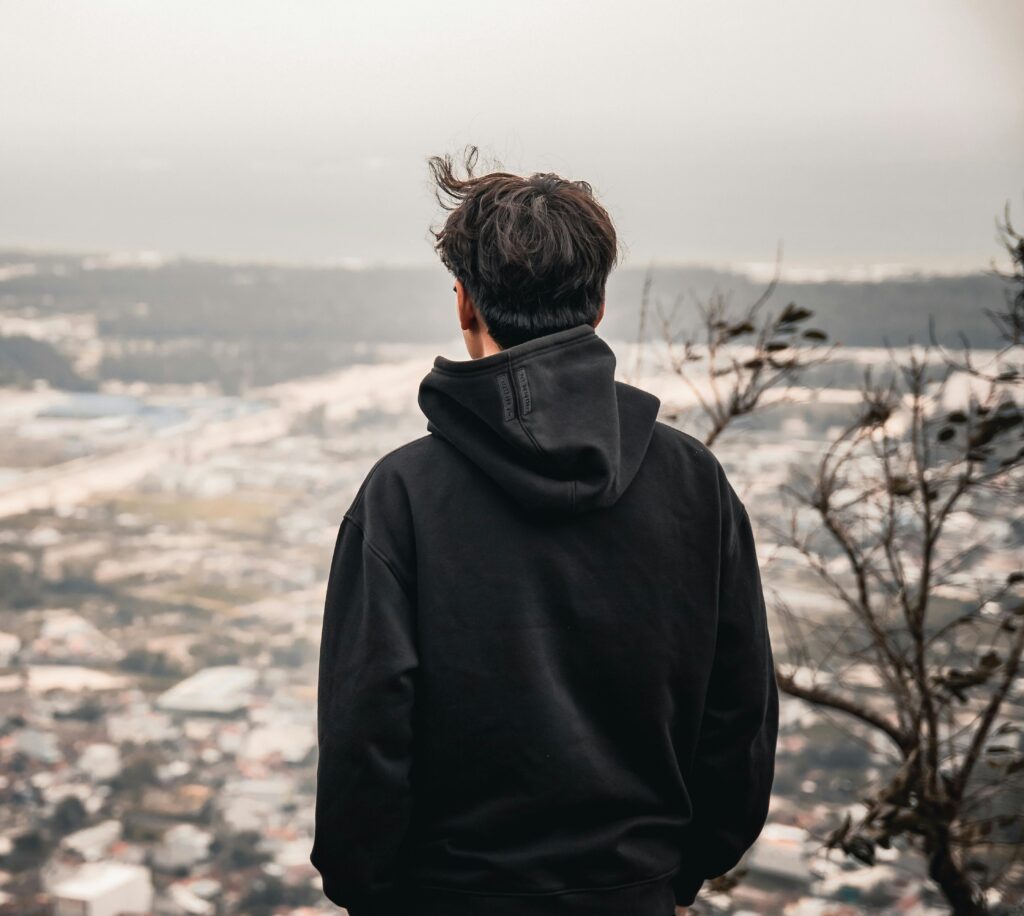 A man facing away from the camera looking down towards a view outside